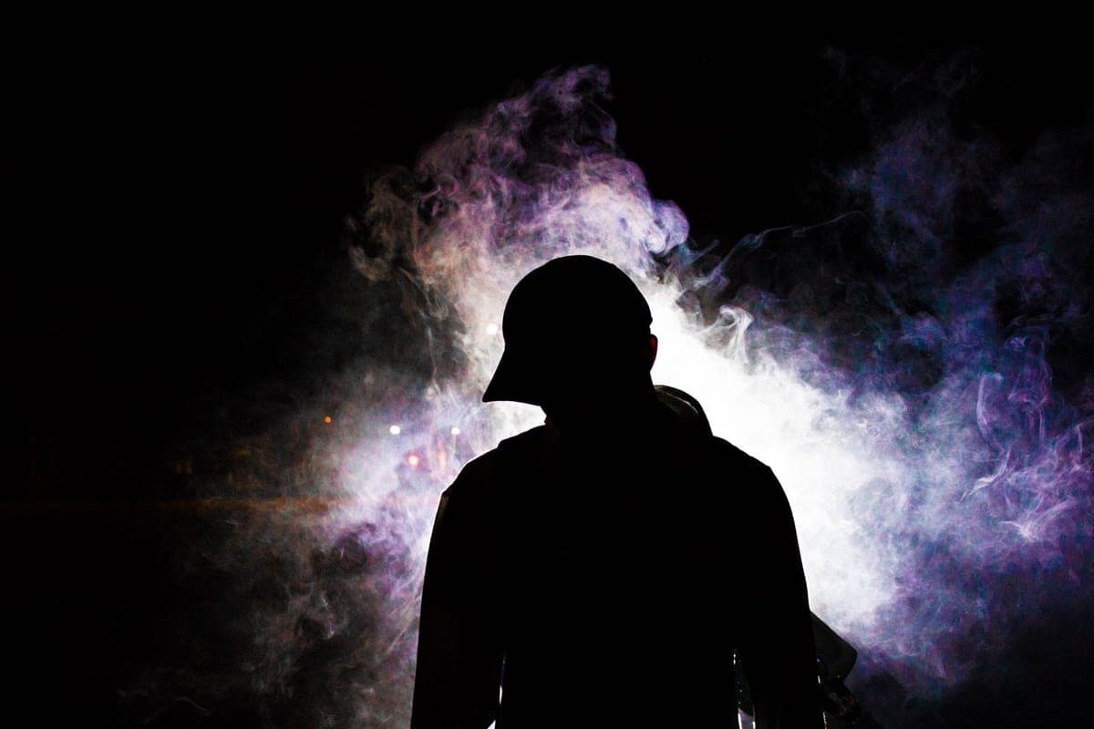 Fog drifting across a dark yard lit by a single colored light