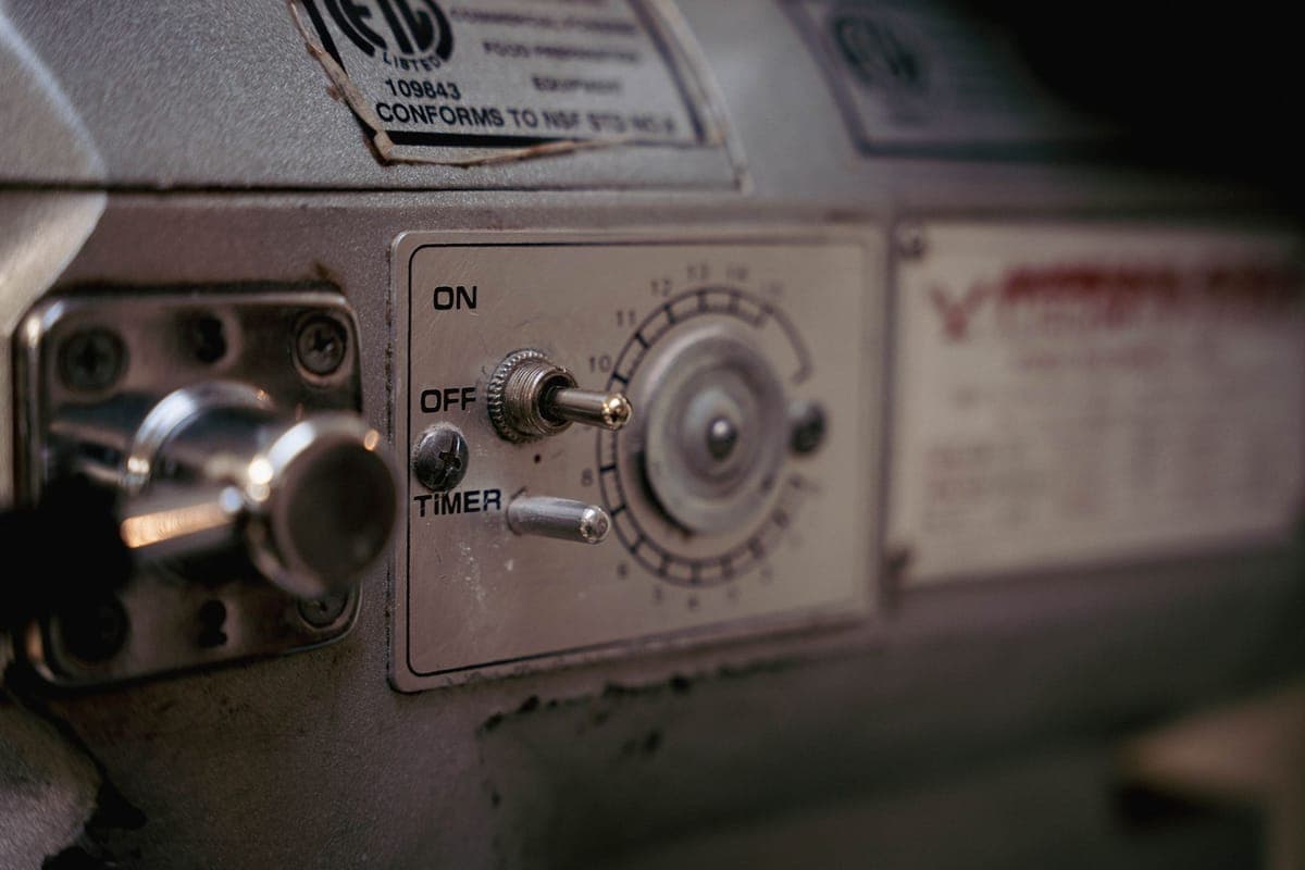 A dial timer and a smart power stake side by side on a garage bench