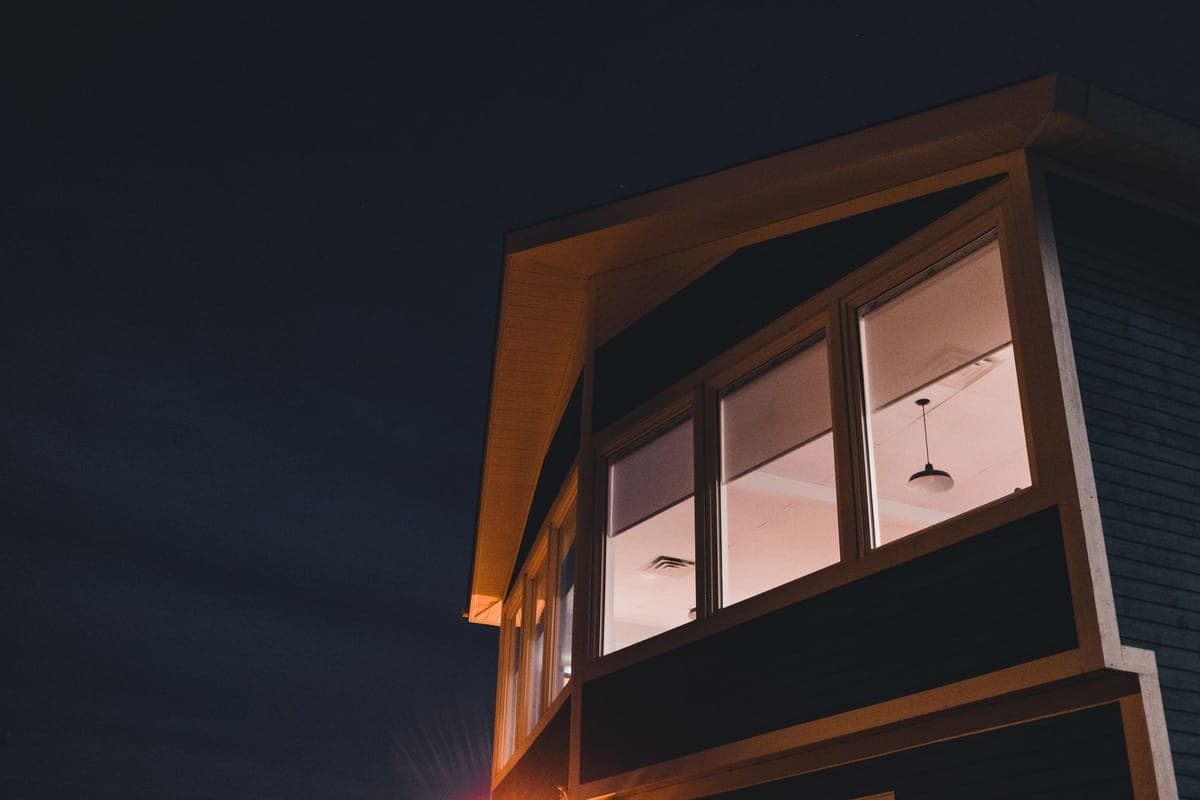A lit window projection beside a larger image cast across a house wall