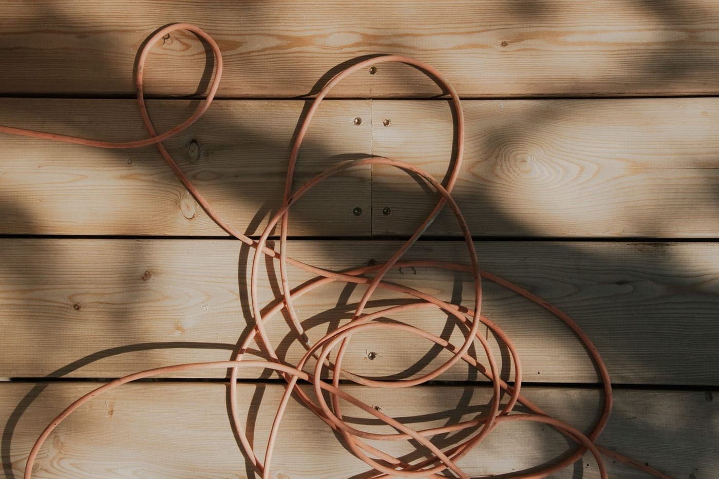 An outdoor extension cord running across grass beside a garden bed