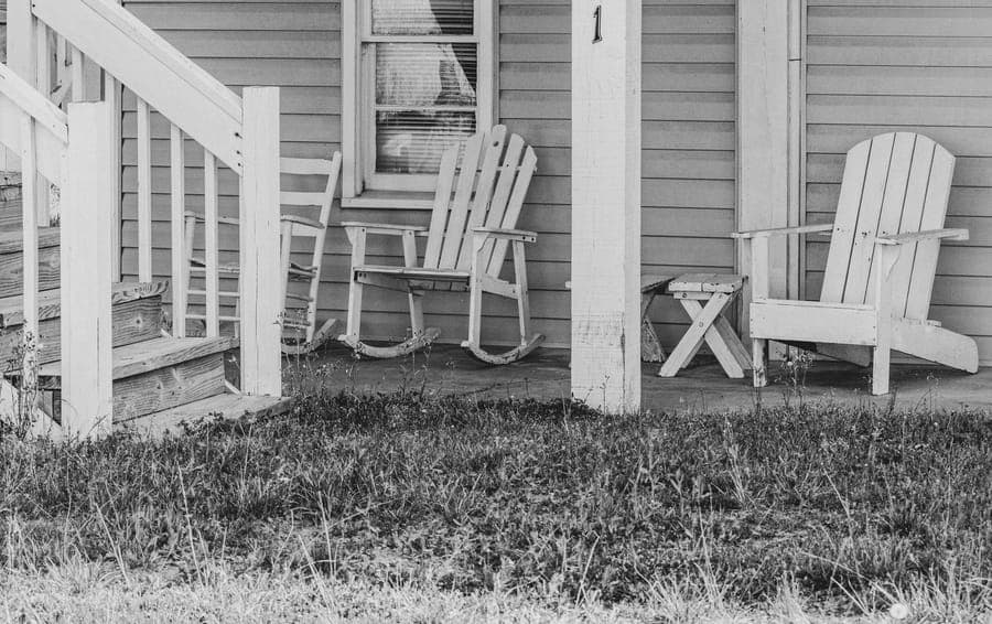 An empty rocking chair on a dark porch lit by a single bulb