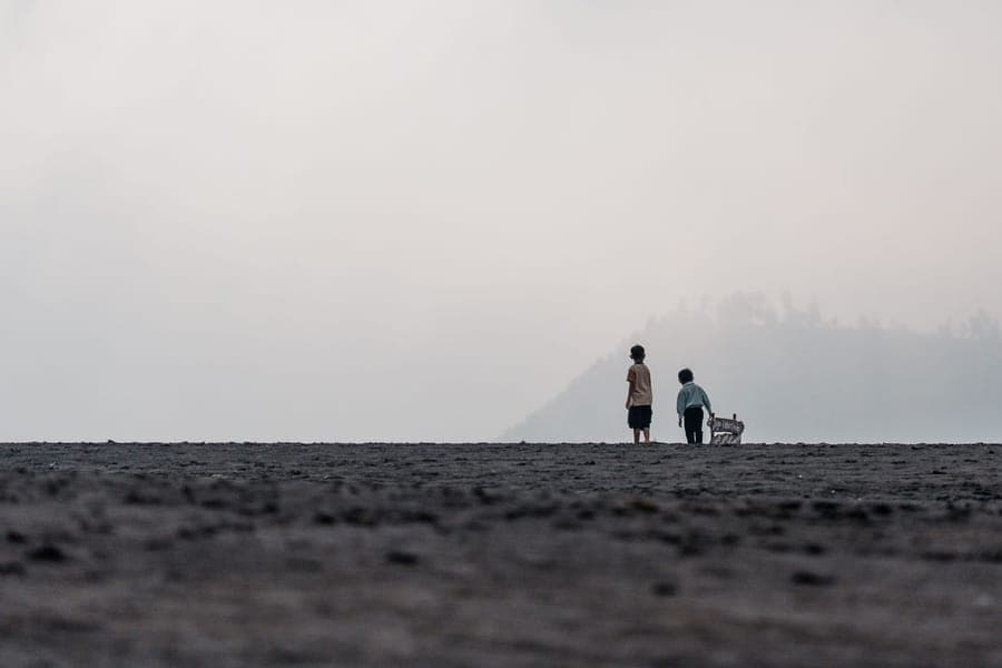 Two small silhouetted figures at the end of a fog-lit path