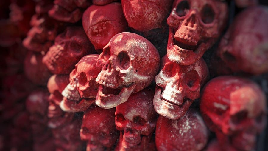 A caged skeletal prop glowing red in a dark garden bed