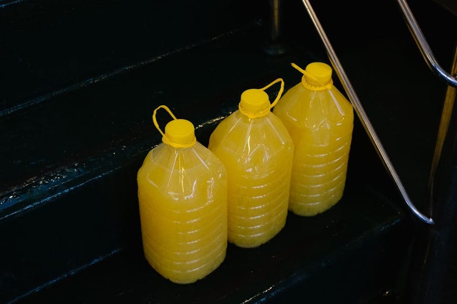 A jug of fog fluid standing beside a fog machine in a garage