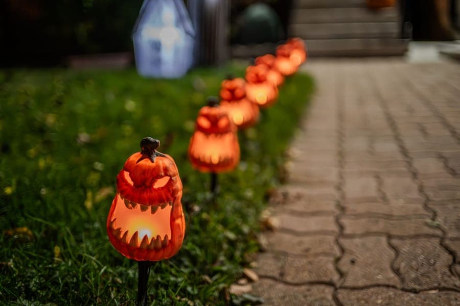 Three lit pumpkin-shaped inflatables on a front lawn after dark