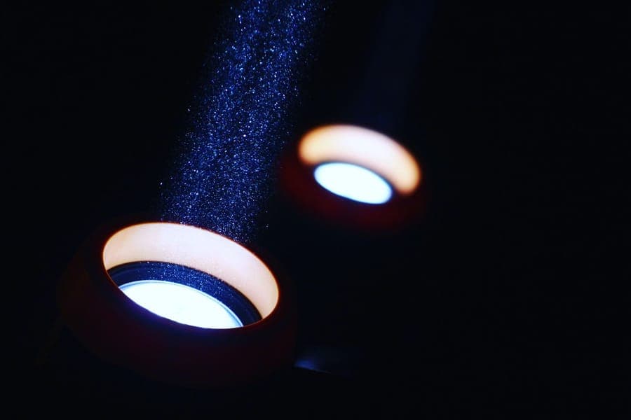A narrow beam of colored light aimed up at a tree trunk