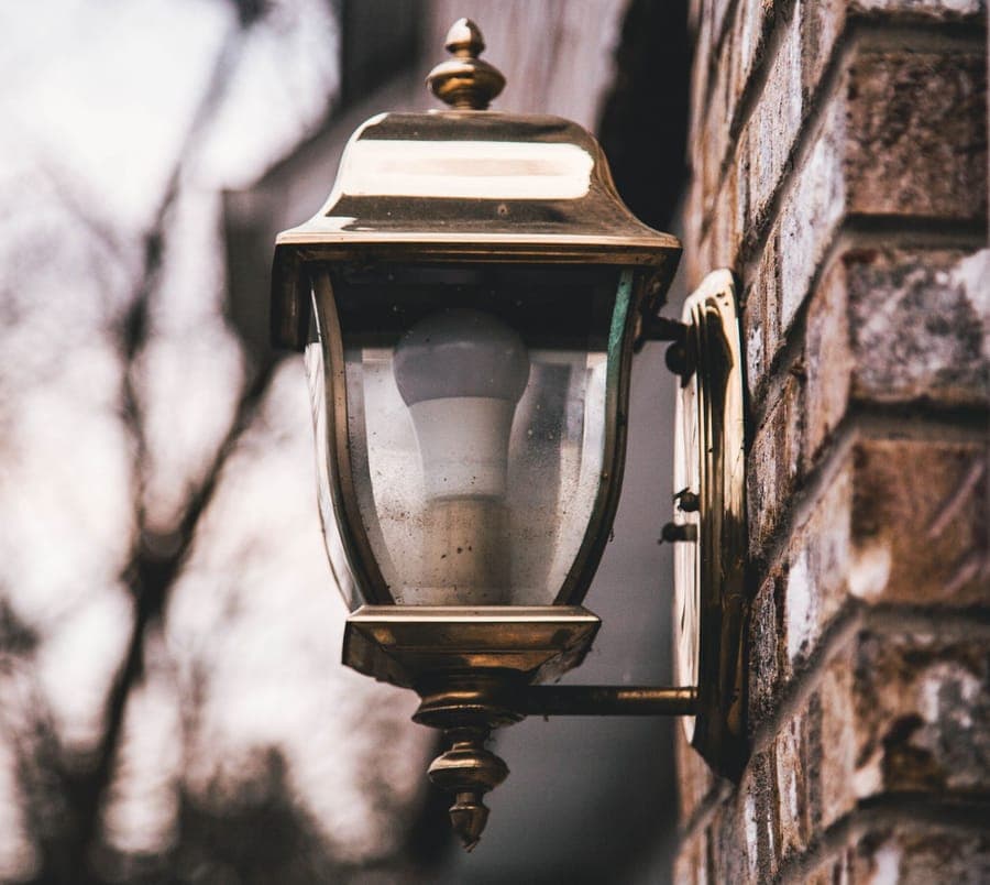 A colored bulb in an outdoor fixture under a porch eave