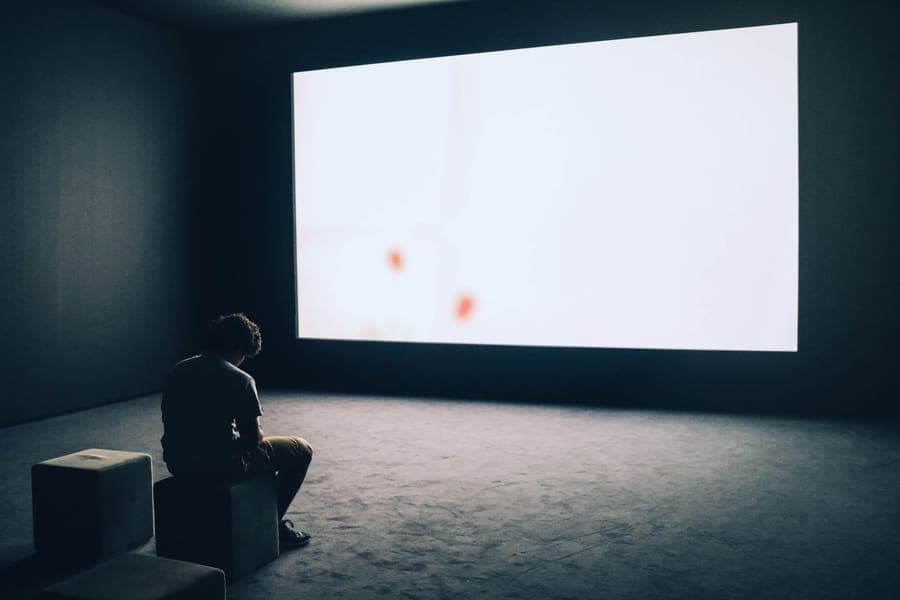 A small projector on a table aimed at a window from inside a dark room