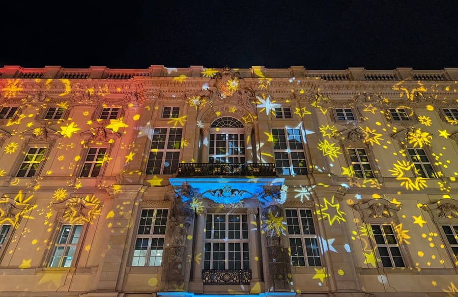 Colored patterns projected across the front wall of a house at night