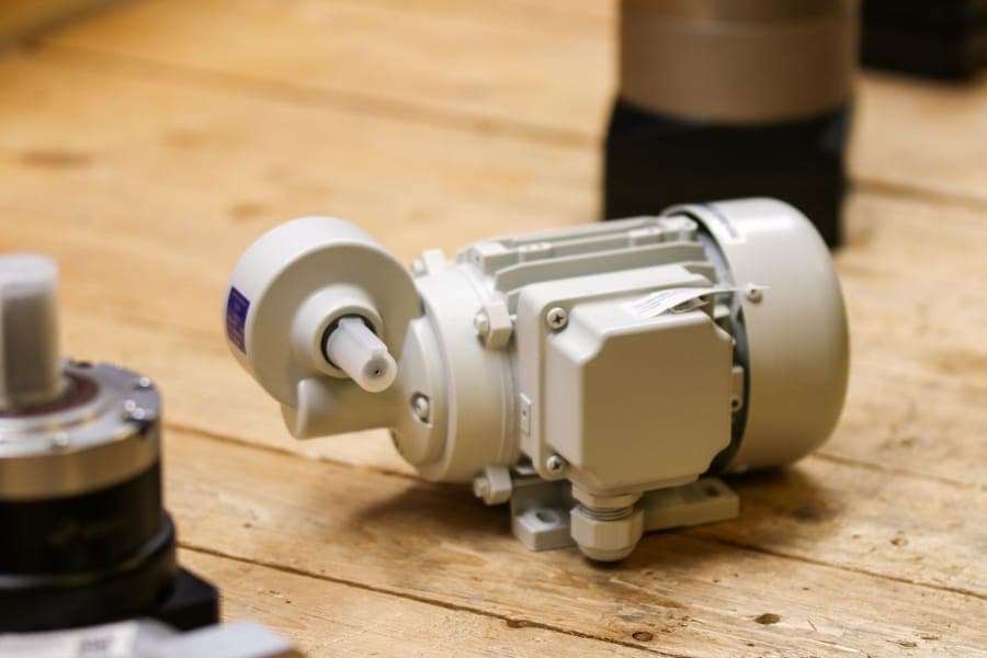 A small electric blower unit sitting on a garage floor next to folded fabric