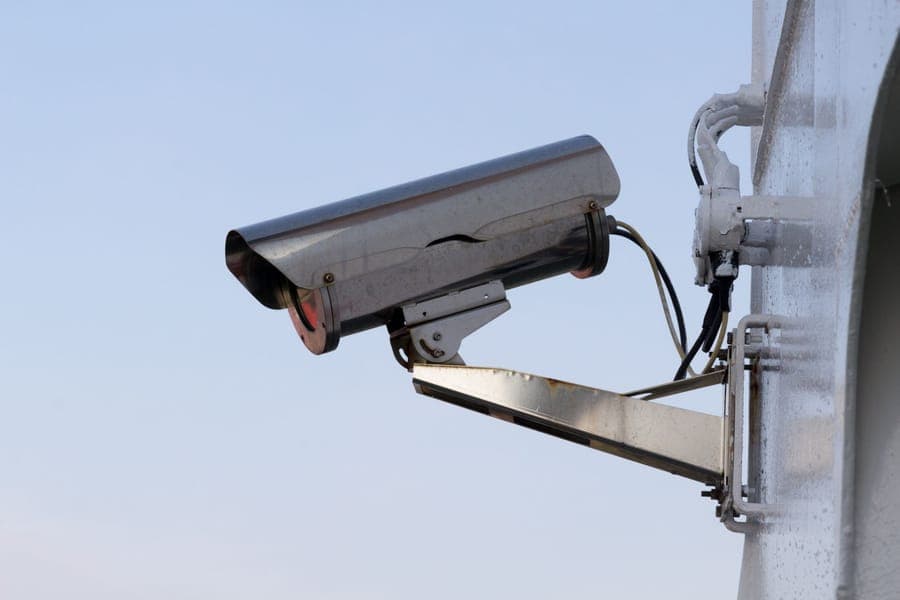A small camera mounted under a porch eave overlooking a front yard