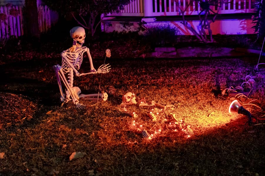 A large skeletal prop clawing up out of a lawn under purple light