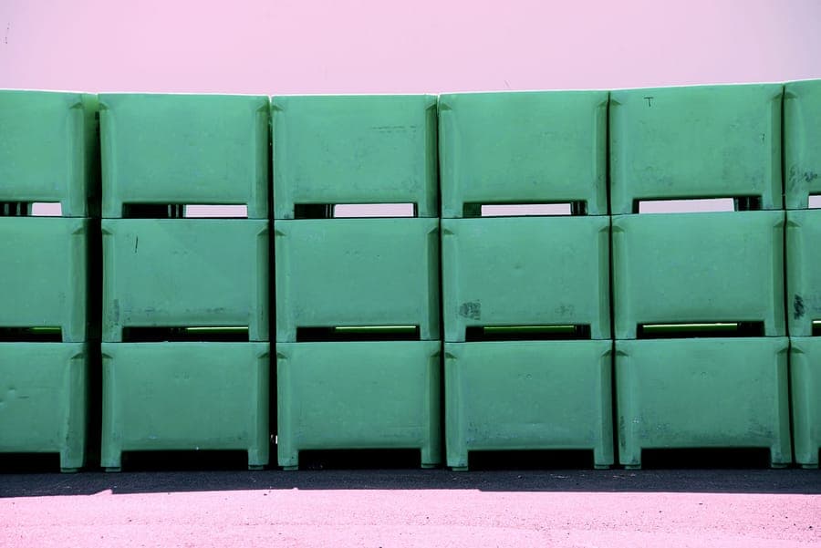 A large heavy-duty tote with a yellow lid sitting on a concrete floor