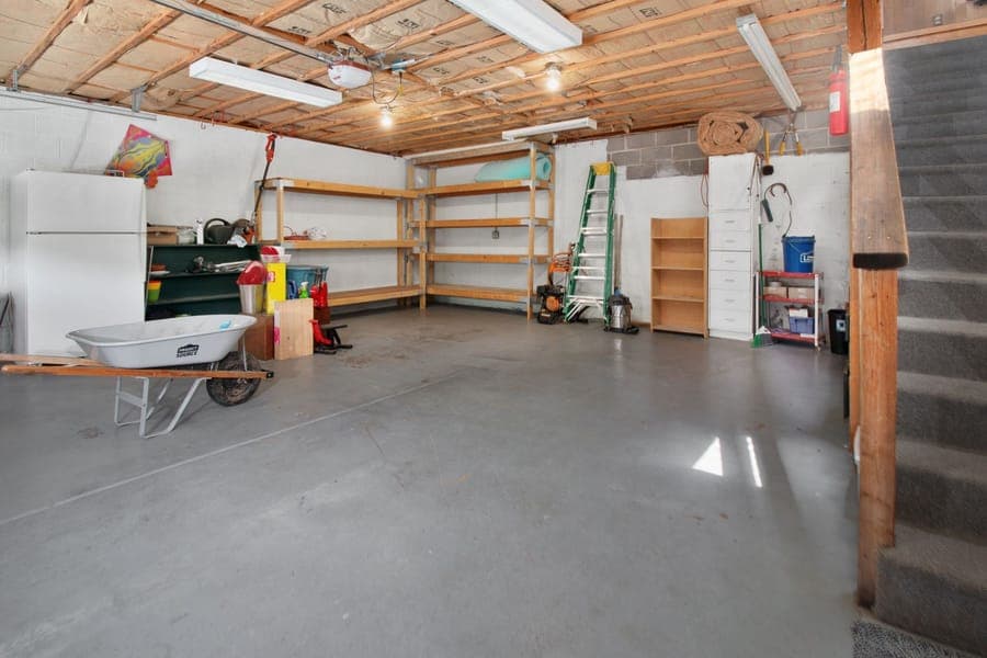 A steel rack suspended from a garage ceiling holding storage boxes